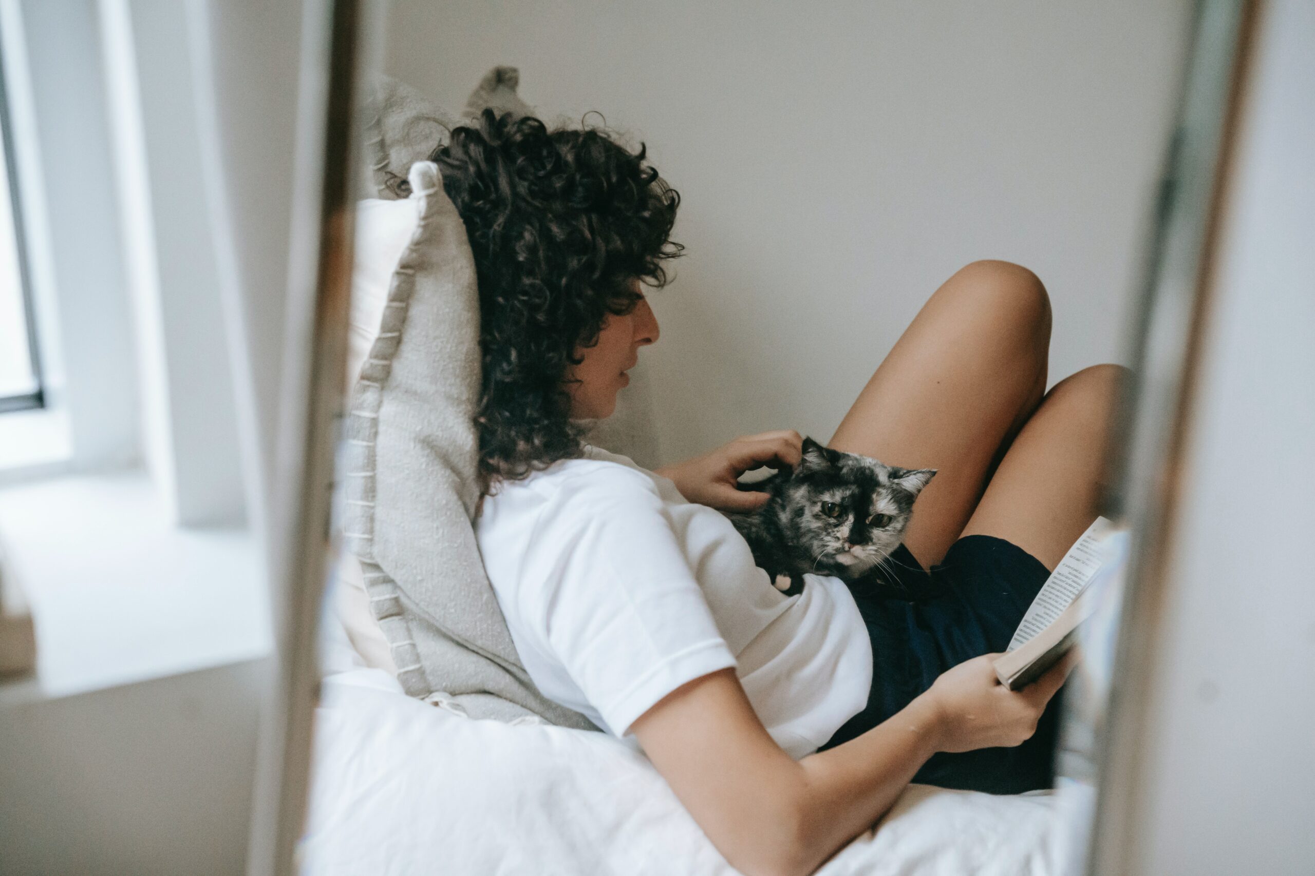 Young woman reading with her cat.